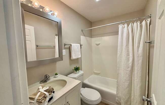 A small bathroom with a white toilet, sink, and shower.
