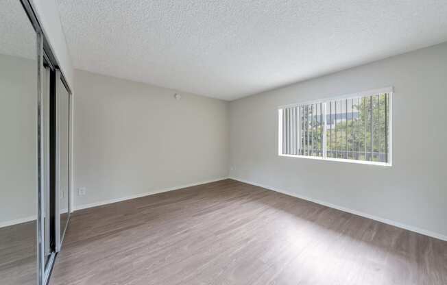 the spacious living room with wood flooring and a window