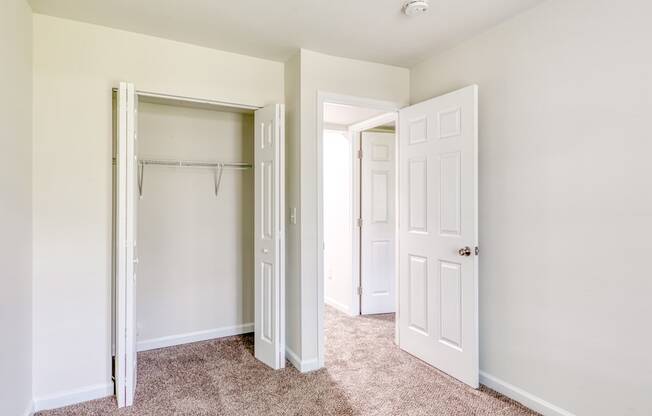 an empty bedroom with white doors and a closet