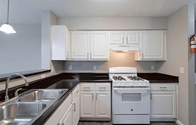 A white stove and oven in a kitchen with white cabinets.