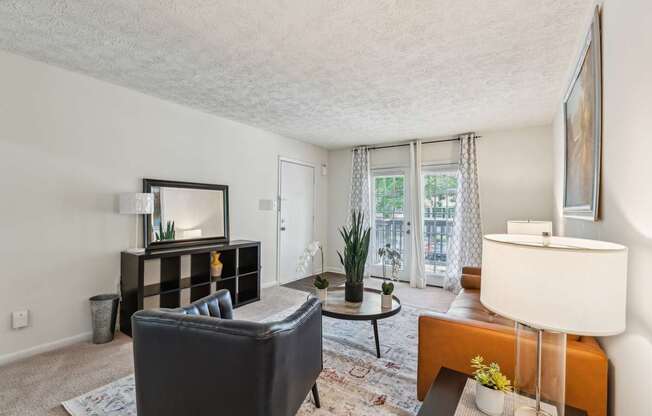 A living room with a black couch, a coffee table, and a large mirror.