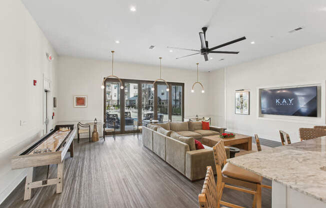 A spacious living room with a pool table and a kitchen area.