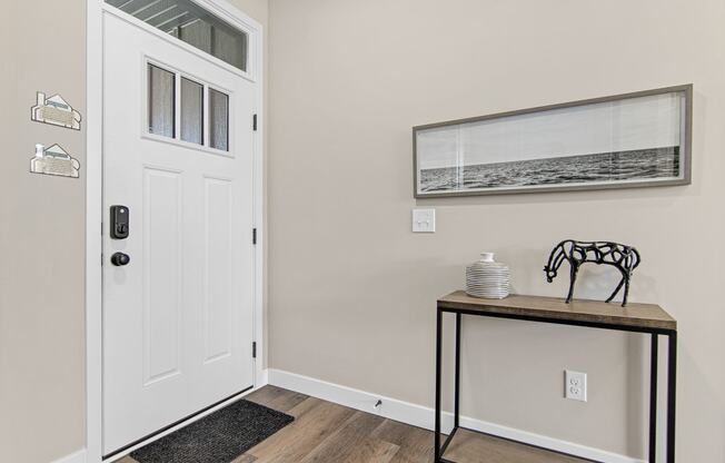 a entryway with a white door and a table with a vase on it