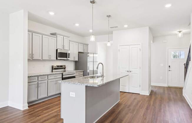 A modern kitchen with a central island and wooden floors.