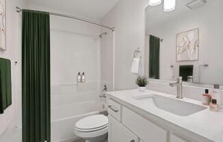 a white bathroom with a green shower curtain and a toilet and sink