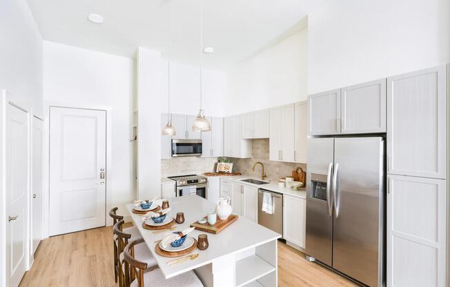 Kitchen with a generous island, pendant lighting, and full-height cabinetry set beneath soaring ceilings for an airy, open feel.