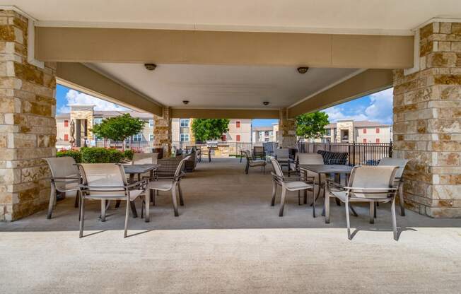 a covered patio with tables and chairs