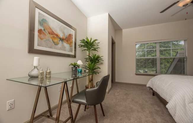 a bedroom with a bed and a glass desk with a chair