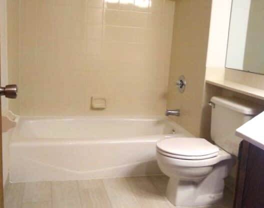 A white toilet sits in a bathroom next to a bathtub.
