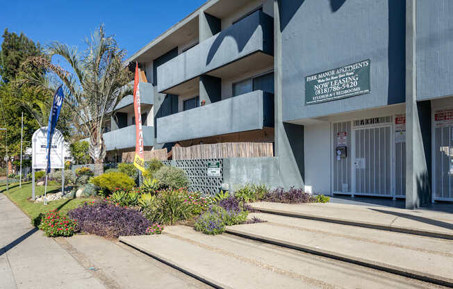 the front of a building with stairs and plants in front of it