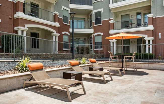 A patio with chairs and an umbrella in front of a building.