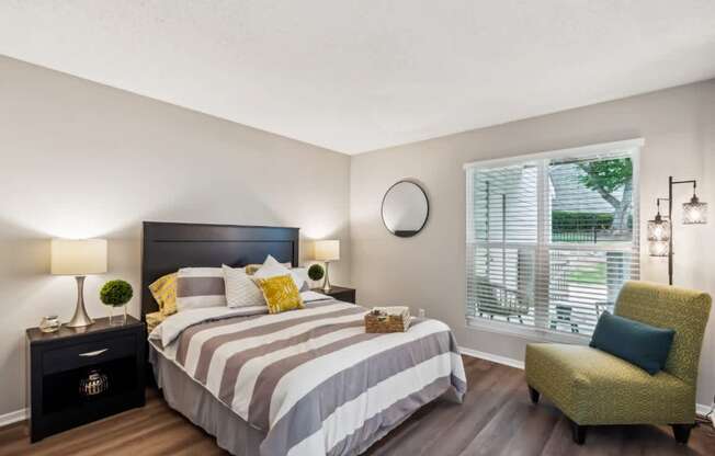 A bedroom with a large bed and a green chair.
