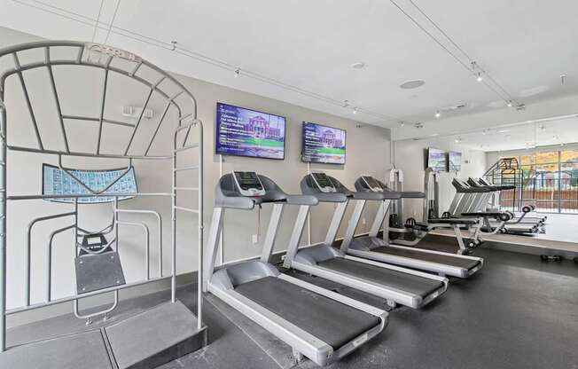 A gym with treadmills and a television screen.
