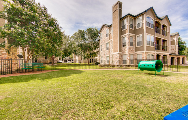 View of Dog Park, Showing Fenced-In Area, Bench, and Track at Stonebriar of Frisco Apartments