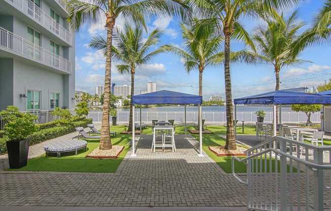 A sundeck with shaded seating and the lagoon in the background at Blue Lagoon 7 Apartments in Miami, FL