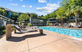 a swimming pool with two lounge chairs next to a resort style pool