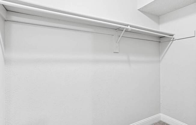 A white wall with a white shelf and a white ceiling.