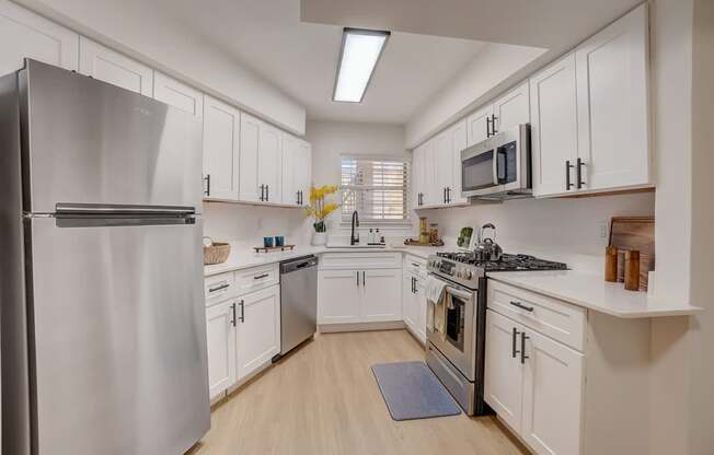 A modern kitchen with white cabinets and stainless steel appliances.