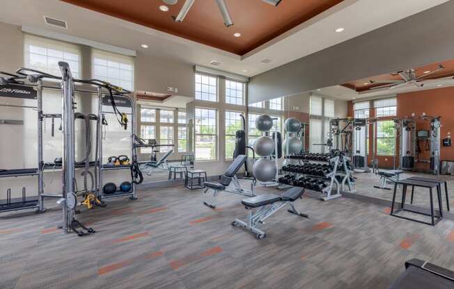 a gym with weights and cardio equipment and windows