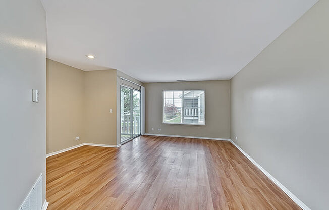 an empty living room with wood floors and a window