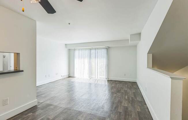 A spacious room with a ceiling fan and wood flooring.