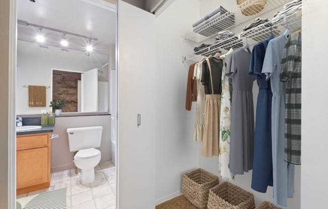 a bathroom with a shower and a closet with clothes and a toilet