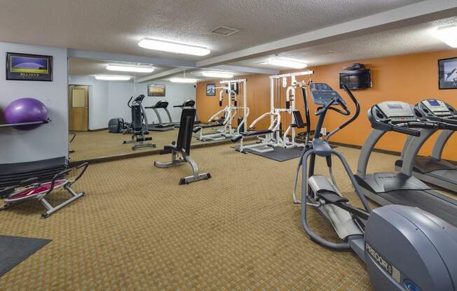 Fitness room with various equipment and a large mirror wall