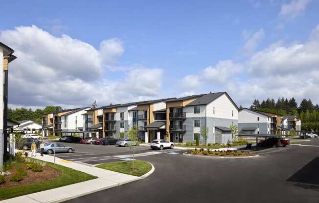 a rendering of an apartment complex with a parking lot in the foreground and buildings in the background