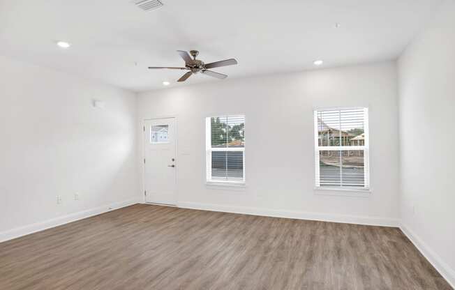 an empty living room with white walls and a ceiling fan