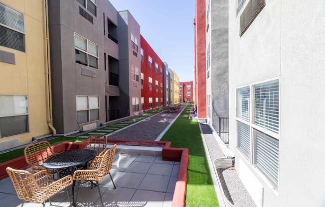 a rendering of a courtyard between two buildings with chairs and a table