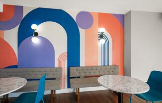 a room with tables and chairs and a wall with a mural