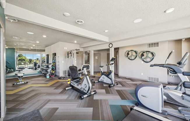 A gym with exercise equipment and a mirror on the wall.
