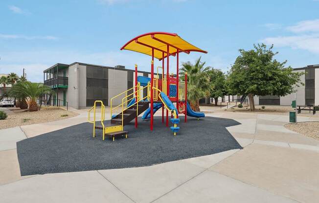 A playground with a yellow umbrella and a slide.