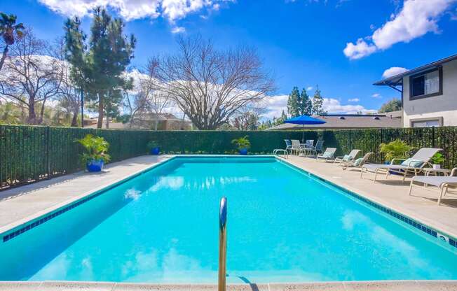 a swimming pool with chairs and umbrellas next to a house