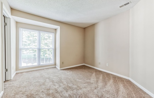 an empty living room with a large window and carpet