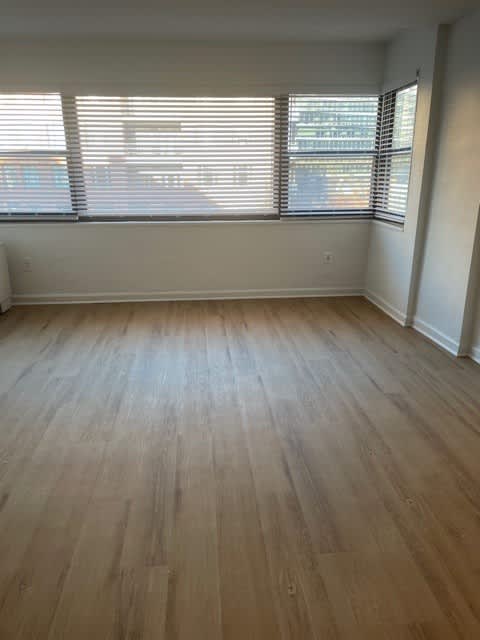 A room with wooden flooring and a window with blinds.
