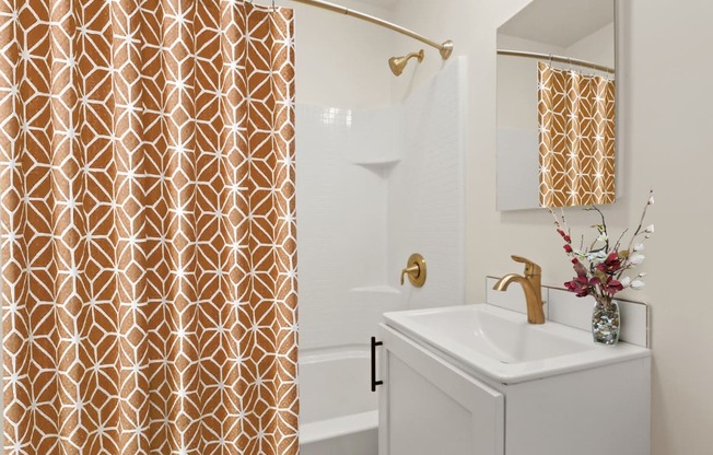 a bathroom with a white sink and gold shower curtain