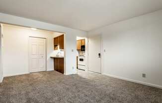 an empty living room and kitchen with white walls and carpet at Pheasant Run in Lafayette, IN 47909