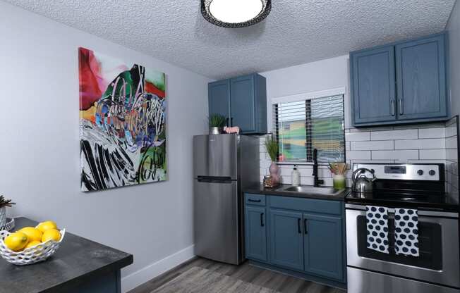 Fusion Las Vegas apartment kitchen with colorful modern painting, large window above the sink, and island with bowl of lemons.