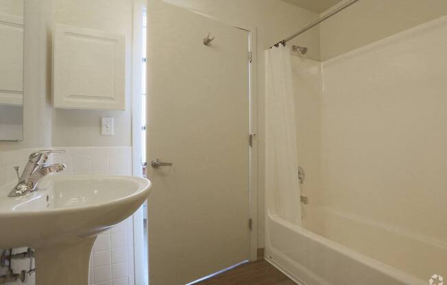 A white bathroom with a sink, mirror, and shower.