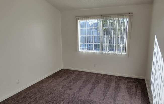 Carpeted bedroom with large window at Northwood Apartments in Upland, California.