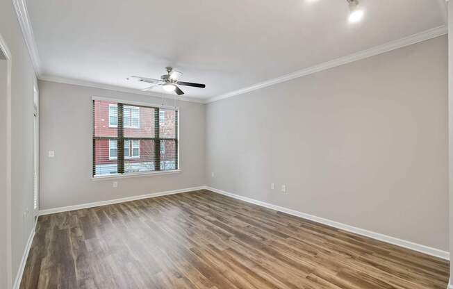 A room with a ceiling fan and a window with a view of a building outside.