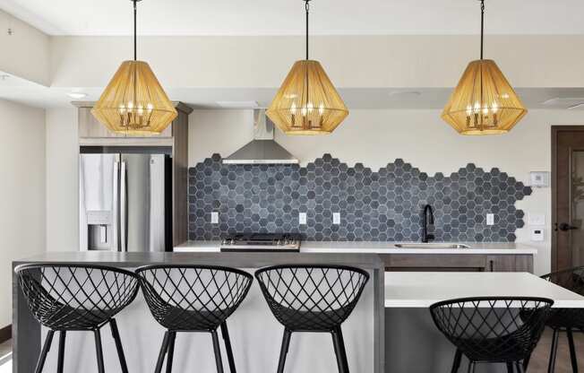 a kitchen with white walls and a large island with four black and white bar stools