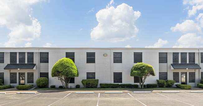 a large white building with trees in front of it at Brookside Apartments, Hewitt, 76643