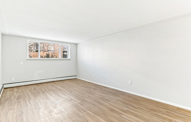 Bright and spacious room with elegant hardwood flooring and large window, perfect for a cozy living area.