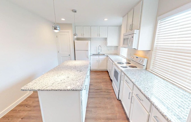 A kitchen with white cabinets and a granite countertop.