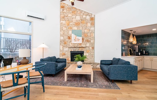 A living room with a stone fireplace and two blue couches.