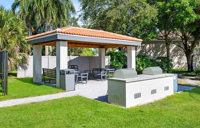 a gazebo with a grill and a table and chairs in a yard