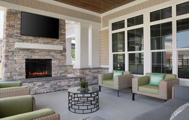 A living room with a stone fireplace and a flat screen TV mounted above it.