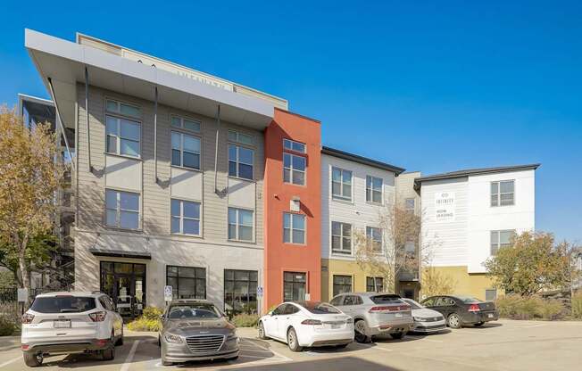 A modern building with a parking lot in front of it at Infinity on the Point Apartments, Dallas 75243